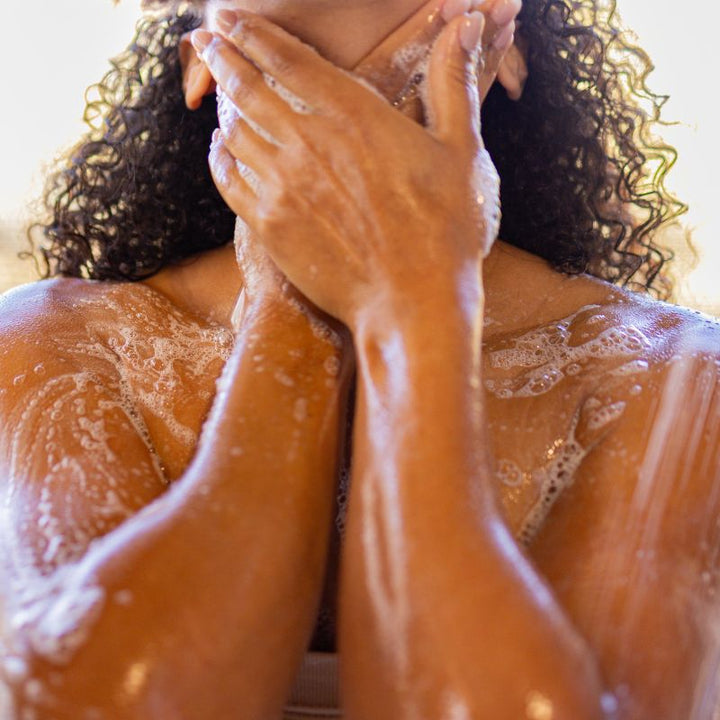 Person with soapy hands and body, focusing on the soap lather from Yaye's body wash.