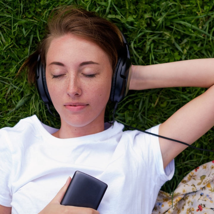 Woman relaxing on grass with headphones – Yaye Aboriginal soundscape audio for mindfulness, nature connection, and mental calm