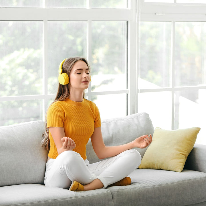 Woman meditating with headphones on couch – Yaye soundscape audio for mindfulness, calm, and Aboriginal-inspired self-care